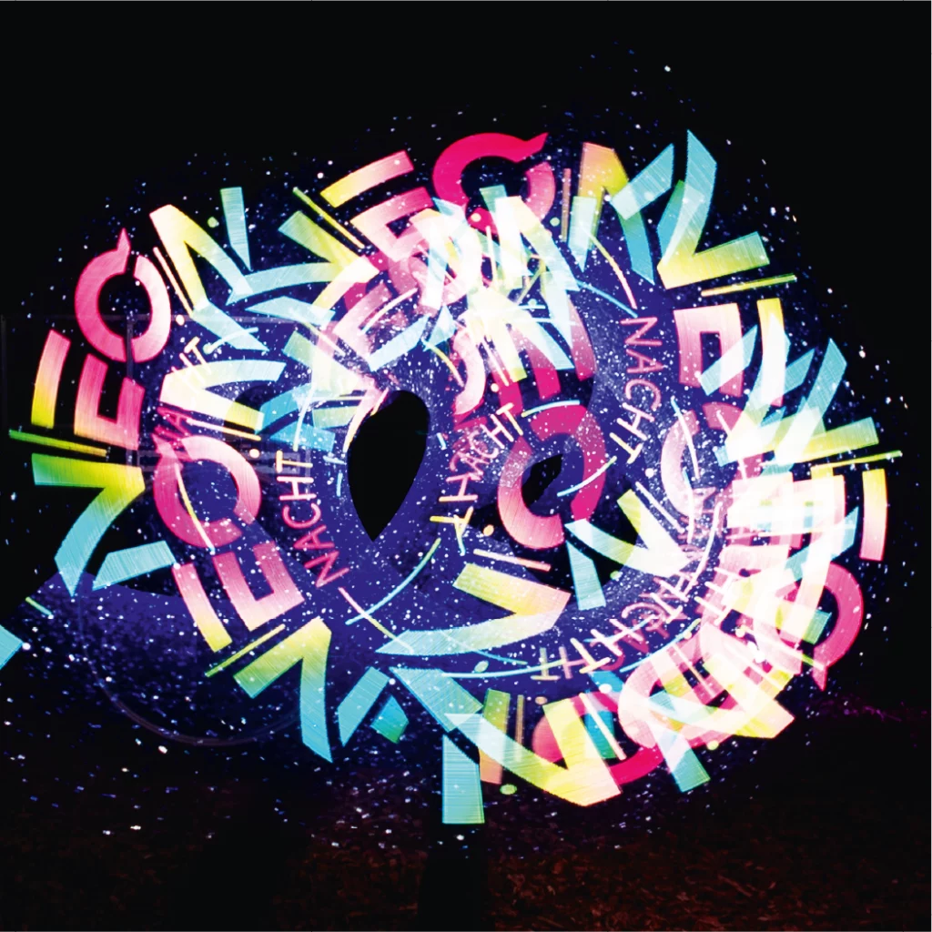 Lichtshow, bei der mehrfach das Logo der NeonNacht in die dunkle Nacht hineingezaubert wurde